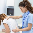 Physiotherapist assisting a patient with lower back pain rehabilitation.